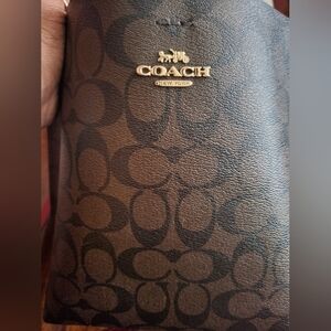 Brown Coach shoulder bag with red strap.